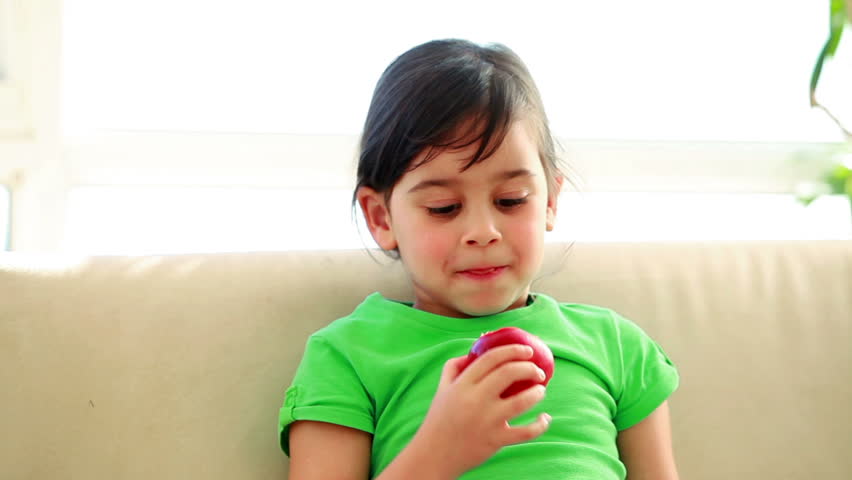Smiling child eating an apple in the living room
