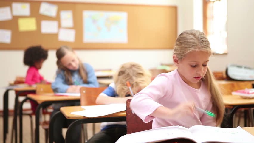 Smiling girl writing on her notebook in the classroom