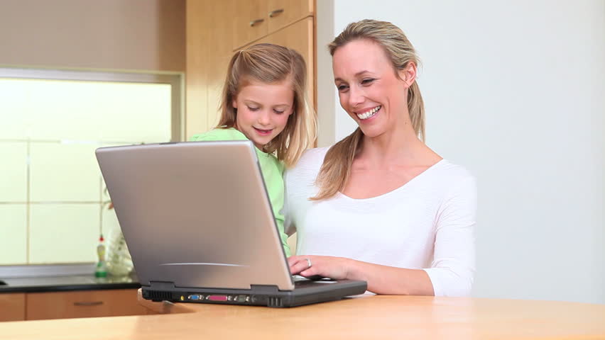 Woman choosing a recipe with her daughter on a laptop