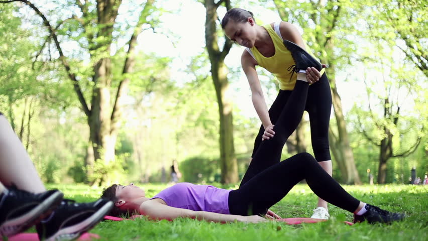 Young women stretching, exercising with personal trainer, dolly shot
