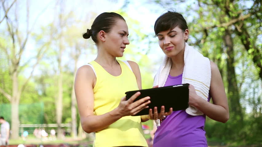 Personal trainer with tablet computer explaining how to exercise, dolly shot
