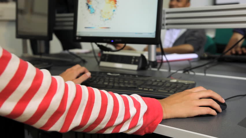Female student working on computer and asking teacher a question