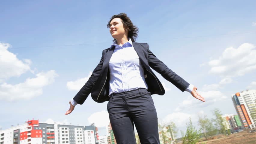 Cheerful young woman in formalwear standing at the open with her hands out, concepts of freedom and success