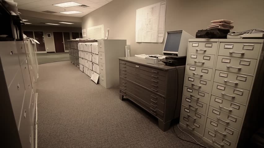A man searches through large filing cabinets at his business