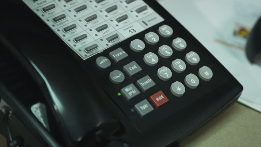 person's hands placing a telephone call on an office phone