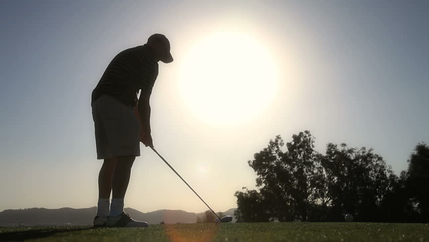 Silhouette of golfer driving the ball