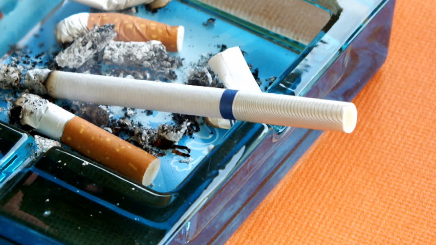 cigarette burned down to the end of a glass ashtray