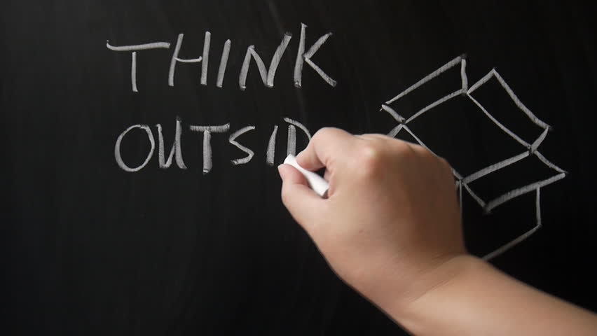 Hand writing "think outside the box" words on the chalkboard
