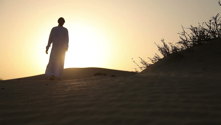 Weary man goes in the desert at sunset