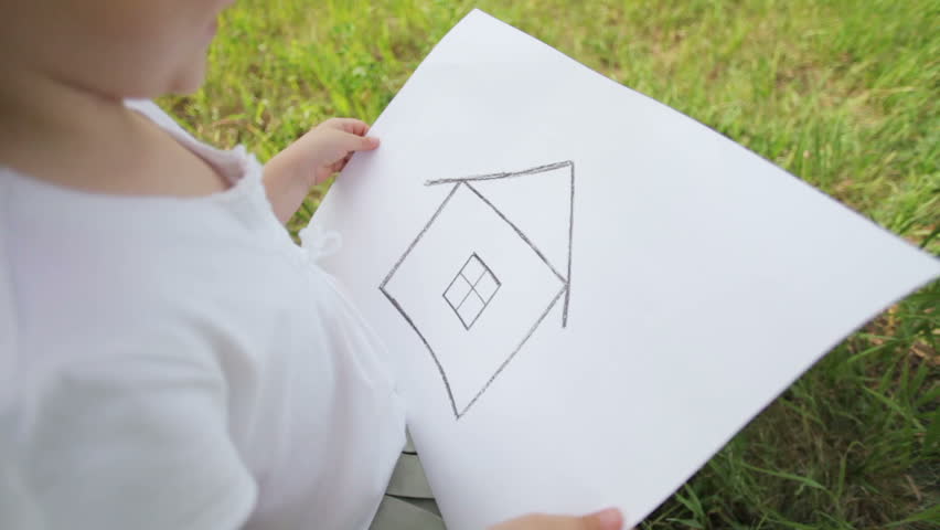 Girl on the field in construction helmet with a picture of a house.