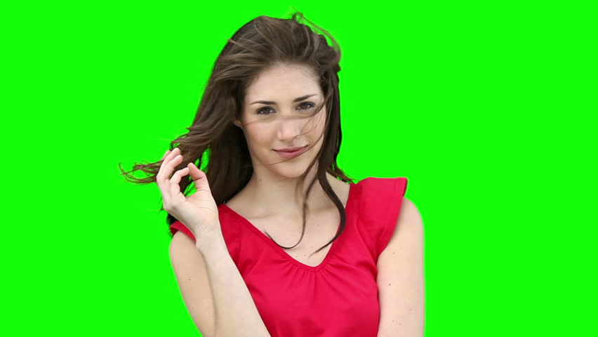Woman feeling her hair as it blows in the wind against a green background