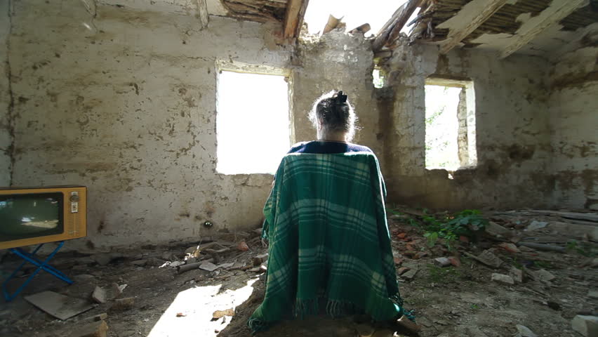 DOLLY: Lonely Old Age. Senior woman looking out the window abandoned house.