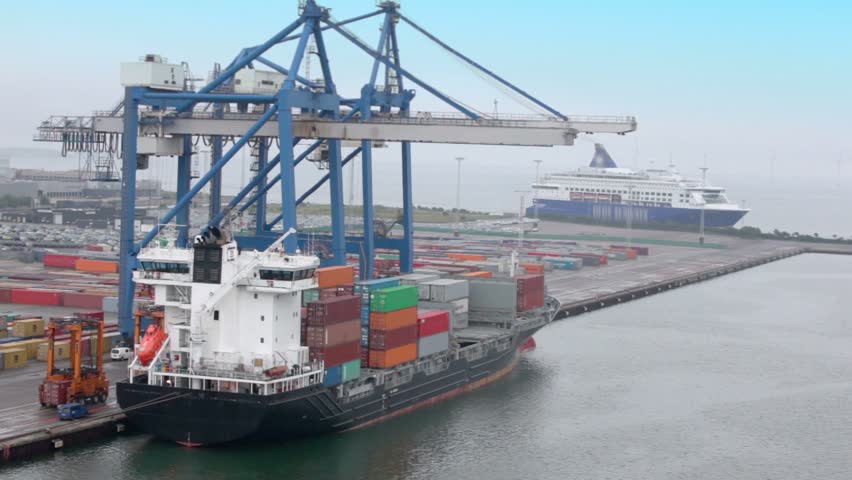 Shipment of cargo in containers to barge by huge crane, passenger liner floats far