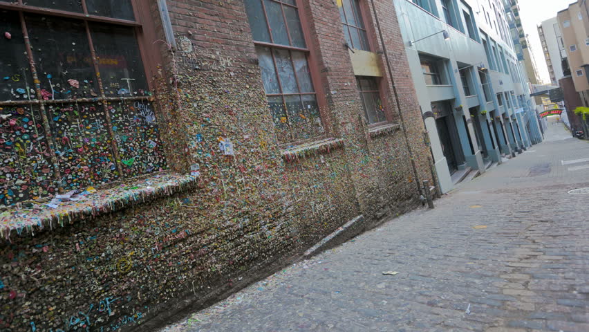 SEATTLE, USA - MAY 12, 2012: Timelapse of People walking by the gum wall on Post Alley in Seattle. the Market Theater Gum Wall is a brick alleyway wall now covered in used chewing gum.