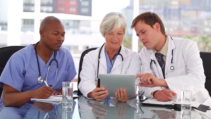 Serious medical team looking at a tablet computer in a bright office