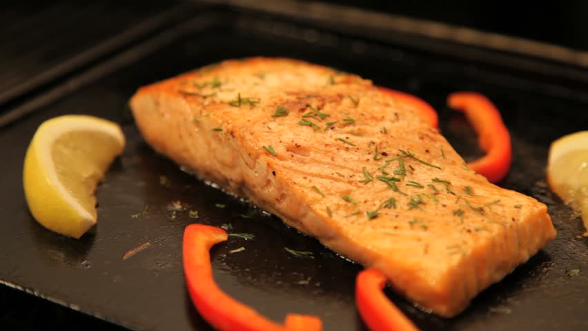 Juicy salmon fillet cooking on hot barbecue, locked down.