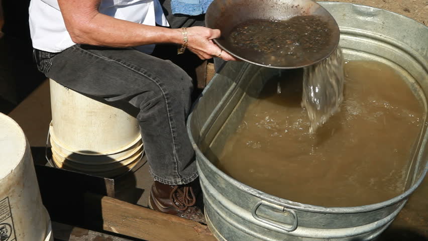 Woman miner giving a gold pan demonstration at a tourist destination in Fairbanks, Alaska video. Woman shows how to pan for gold. Tourism economic boost to economy.