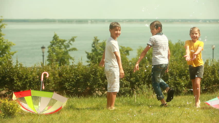 Playful kids trying to escape water sprayed from sprinkler system