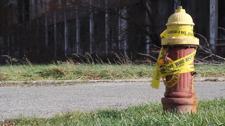 Urban blight in Detroit, Michigan. An old fire hydrant wrapped in caution tape near a decaying, abandoned factory.