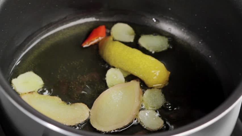 Heating ginger, lemon zest and chilli in oil