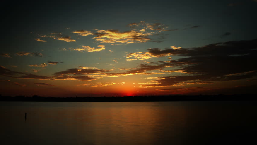 Beautiful clouds over a lake at sunrise, with brilliant colors. HD 1080p time lapse. 