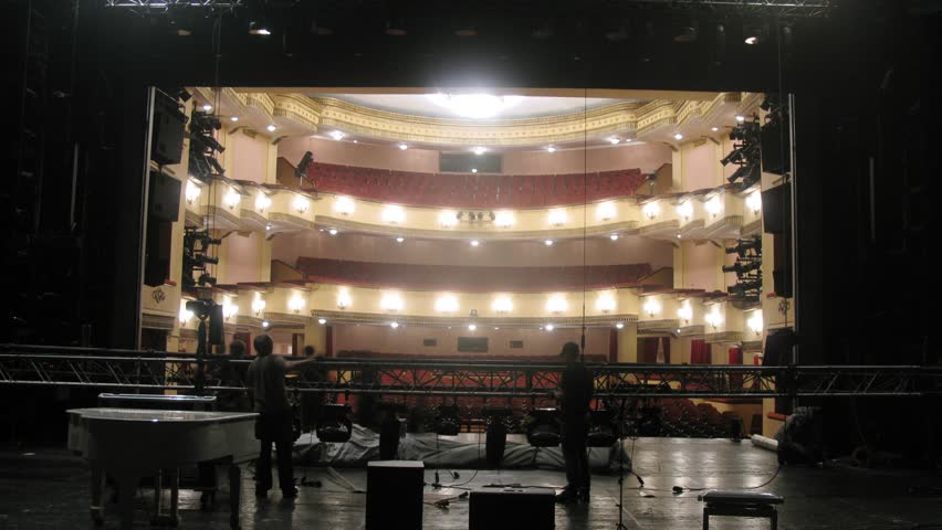 Working scenes dismantle scenery after performance against an empty spectator hall in theatre, time lapse