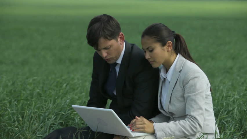 Partners sitting on the grass and discussing business matters
