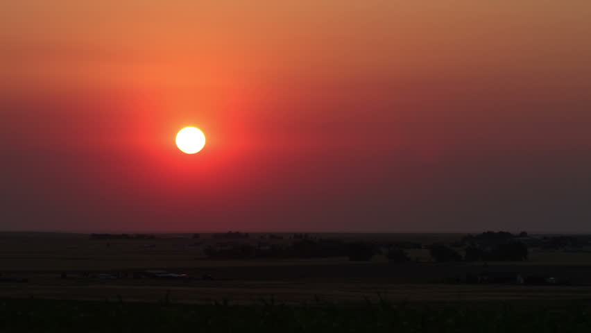 Sunrise on the plains, obscured by smoke from a brush fire in the summer heat and drought conditions. HD 1080p time lapse.