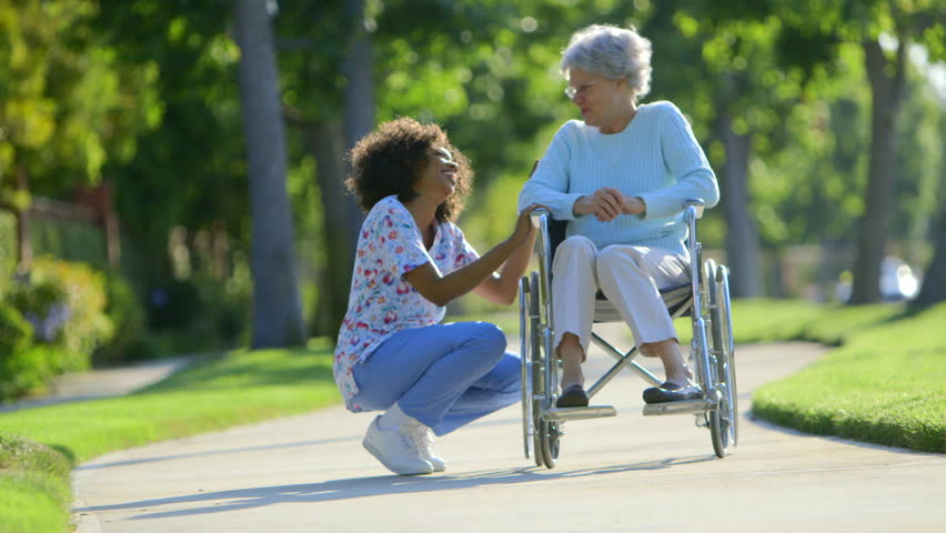 Nurse talking with elderly woman in wheelchair