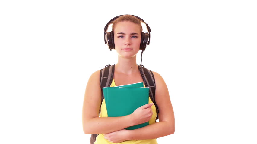 Smiling schoolgirl with backpack and textbooks listening music
