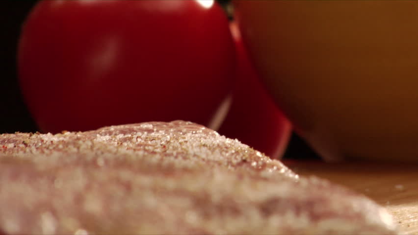Chef sprinkles salt and dry rub on steak