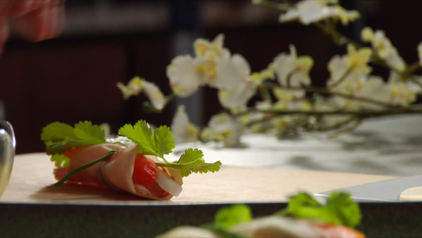 Chef prepares Asian shrimp appetizer and camera pan over as he places it on a serving plate.