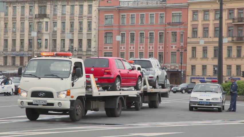 SAINT PETERSBURG, RUSSIA - AUGUST 2: Police inspector stand near two breakdown trucks with cars on Uprising square with traffic on August 2, 2011 in Saint Petersburg, Russia.
