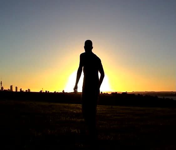 A youth jumps against the backdrop of a setting sun.