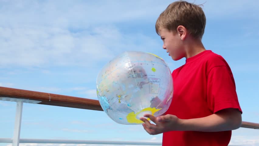Little boy stand near railing and hold inflated ball with earth texture