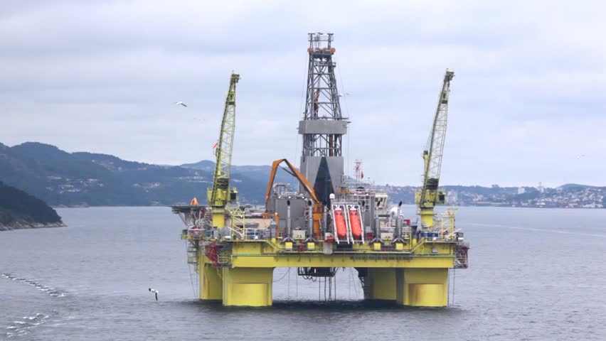 Drilling platform Coslpioner stands in Stavanger gulf against mountains
