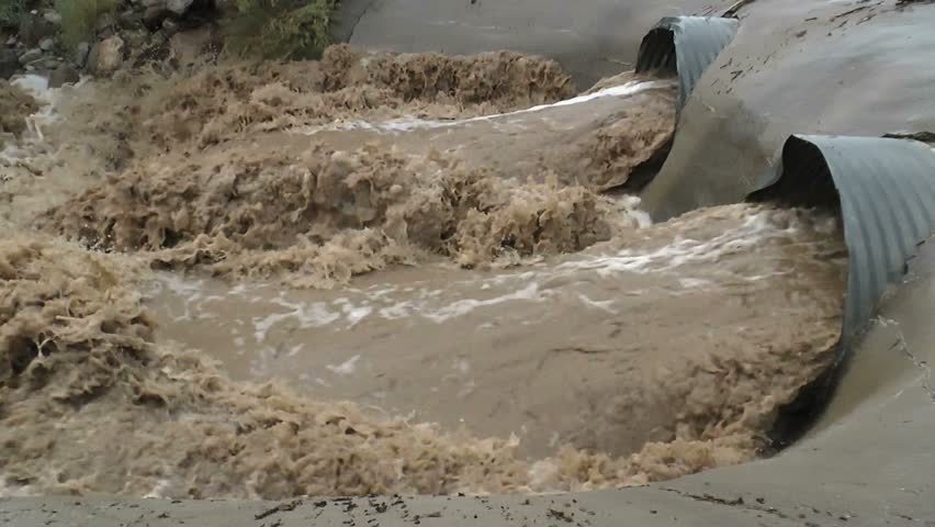 Pan left, Water surges through storm drain or ducts into Arizona desert wash after summer, monsoon rains.108/600p