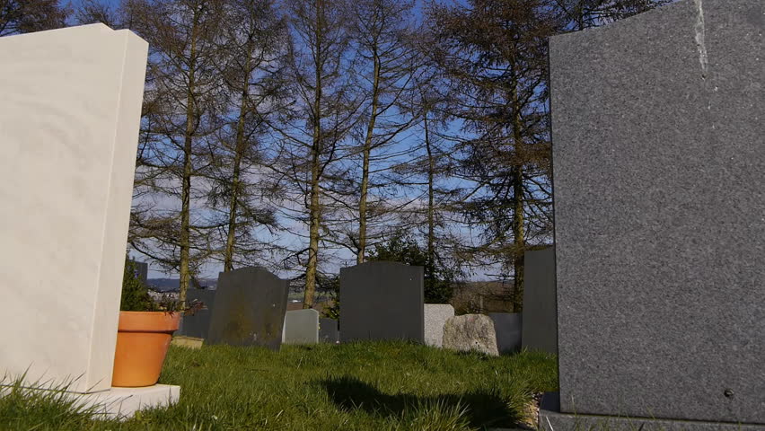 Camera tracks past some gravestones ending on a big white marble gravestone.