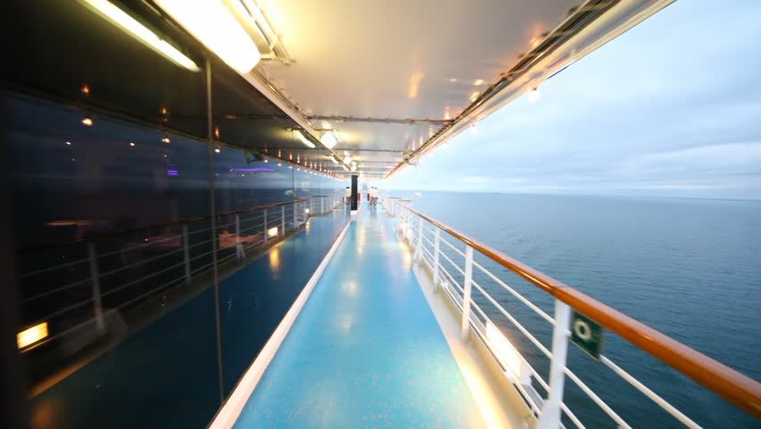 movement on ship deck, with restaurant behind glass at left and sea on right