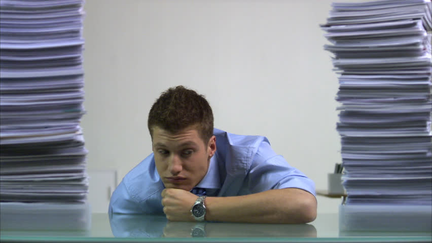 A tired man between piles of paper