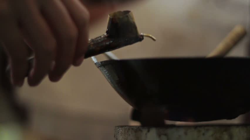 Tjanting dips into wax for hand painted batik application