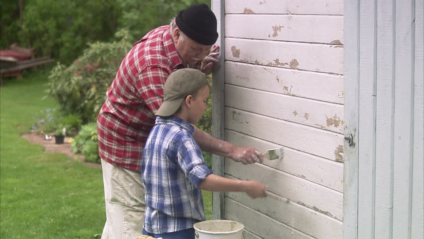 Grandfather and grandson painting their summer cottage