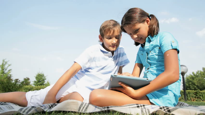 Cute girl explaining to his brother how to use a tablet pc