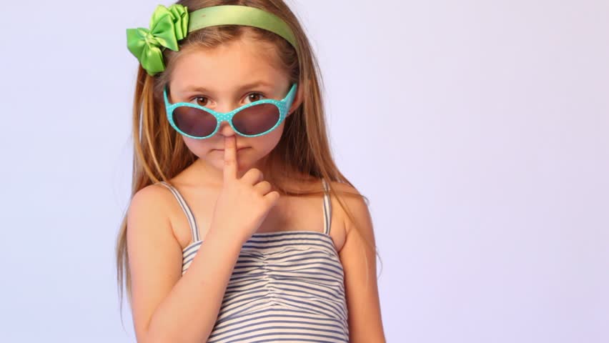 girl wearing spectacles on nose pulls them finger over eyes and sticks out lips