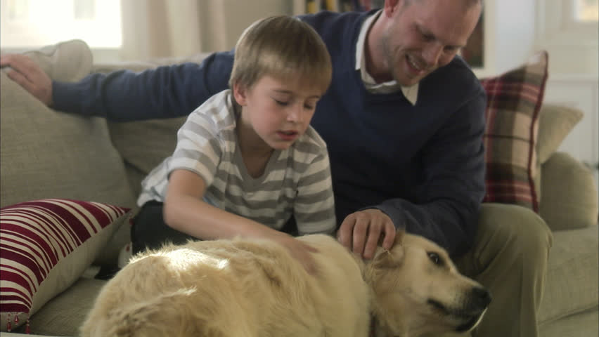 Father and son sitting in a sofa with a dog