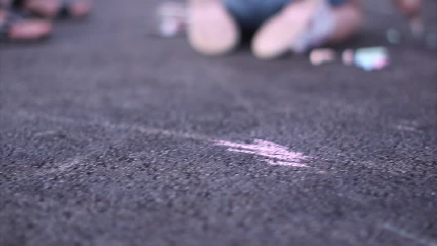 Kids drawing with chalk on the playground. Close up shot of a kid's hand drawing abstract composition.