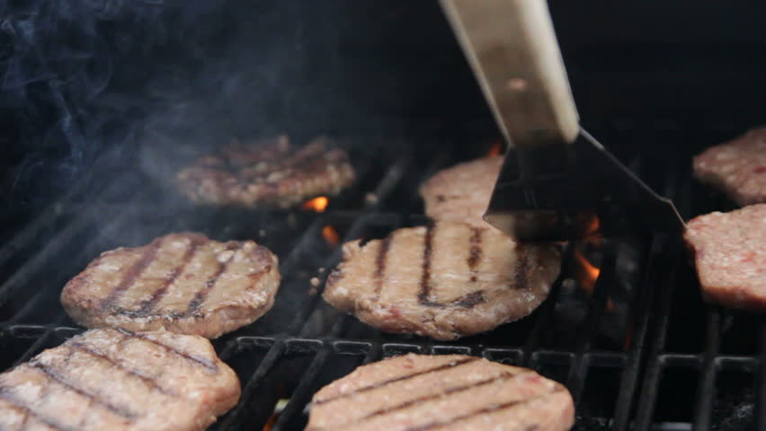 Dolly of burgers being flip as they cook on a grill. Sequence. 
