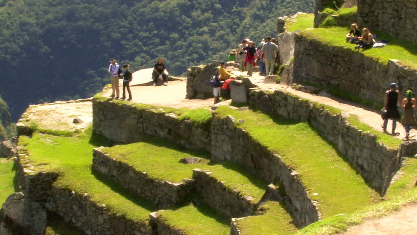 MANCHU PICCHU, PERU - April 2009: Tourists on the grassy steps of Machu Picchu, Peru