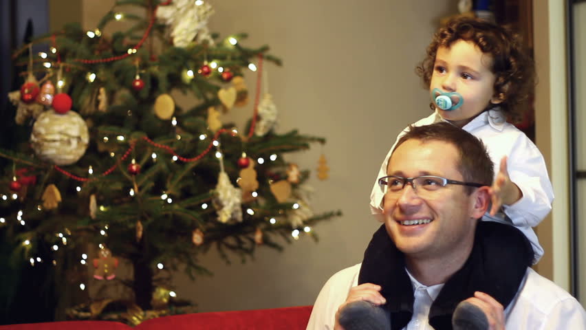 Portrait of father giving son piggyback ride near christmas tree