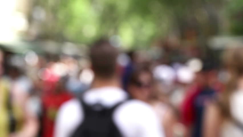 Busy anonymous people out of focus are walking in the park.